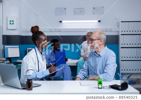 Hospital medic expert writing down sick senior patient illness symptoms while prescribing antibiotic medicine. Clinic specialist analyzing patient condition and offering treatment for disease 89540325