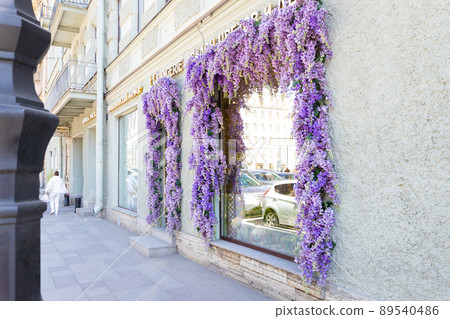Decoration with purple decorative artificial Delphinium flowers over an entrance of store and shop windows. Vintage exterior 89540486