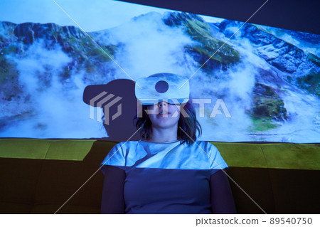 Woman uses virtual reality glasses to go to another point of light and see mountains. Woman uses virtual reality glasses to go to another point of light and see mountains. 89540750