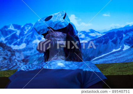 Woman uses virtual reality glasses to go to another point of light and see mountains. Woman uses virtual reality glasses to go to another point of light and see mountains. 89540751