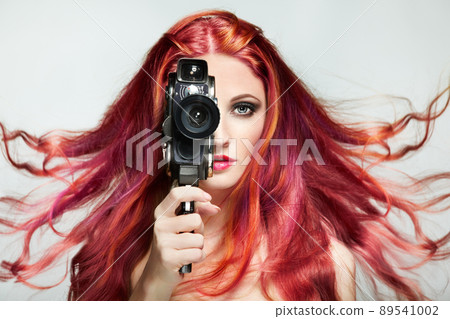 Beautiful young woman using a retro video camera Beautiful young woman using a retro video camera 89541002