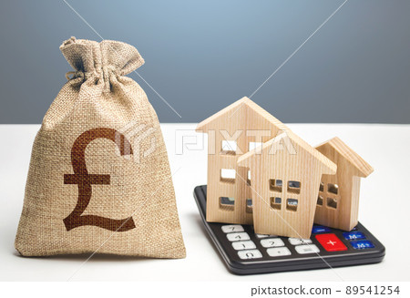 Houses on a calculator and british pound sterling money bag. Buying and selling. Real estate valuation. Building maintenance. Mortgage loan. Utilities and services expenses. Taxes, budget. 89541254