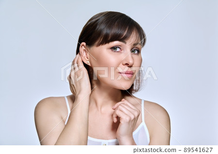 Portrait of middle aged woman looking at camera on light studio background Portrait of middle aged woman looking at camera on light studio background 89541627