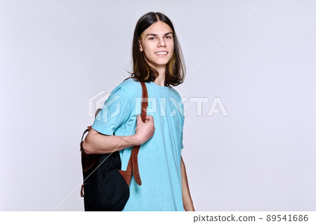 Portrait of positive student guy with backpack looking at camera, studio light background Portrait of positive student guy with backpack looking at camera, studio light background 89541686