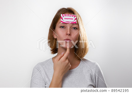 Finance and banking. Portrait of a young blonde who has a Bank card attached to her forehead with the words shopping . White background and copy space Finance and banking. Portrait of a young blonde who has a Bank card attached to her forehead with the words shopping . White background and copy space 89542195