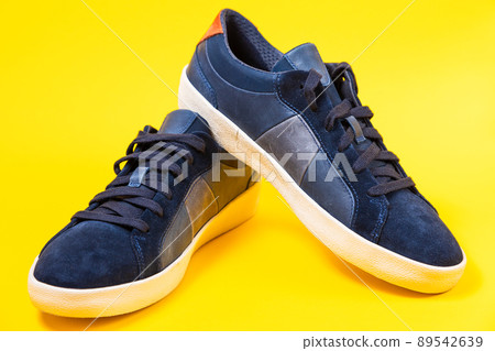 Male's new sneakers made of blue leather beautifully laid out on a yellow background. Close up 89542639