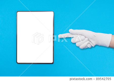 Digital tablet on blue background. A gloved hand points a finger at the tablet. Mock up. The concept of digital devices and communication Digital tablet on blue background. A gloved hand points a finger at the tablet. Mock up. The concept of digital devices and communication 89542705