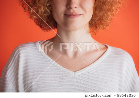 Cropped image of red-haired woman posing in white T-shirt isolated over red studio background 89542856
