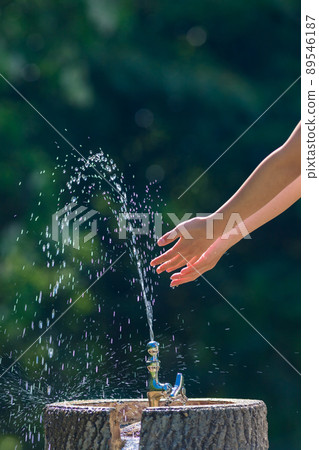 A cute elementary school girl washing her hands in a park in the middle of summer A cute elementary school girl washing her hands in a park in the middle of summer 89546187