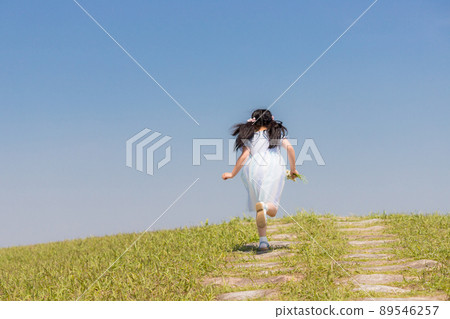 An elementary school girl playing in the field in early summer An elementary school girl playing in the field in early summer 89546257