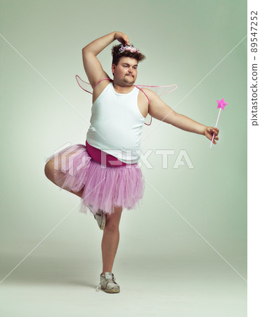I do ballet. An overweight man comically dressed-up in a pink fairy costume doing ballet. I do ballet. An overweight man comically dressed-up in a pink fairy costume doing ballet. 89547252
