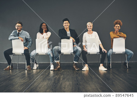 The row of success. Studio shot of a diverse group of creative employees sitting on chairs inside. The row of success. Studio shot of a diverse group of creative employees sitting on chairs inside. 89547645
