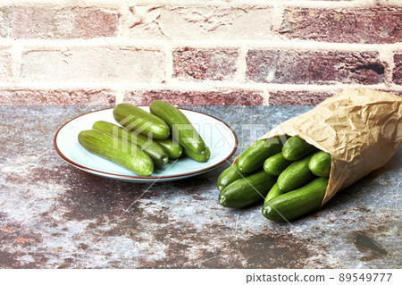 Healthy organic baby cucumbers in a plate and a paper bag. Healthy snack food 89549777