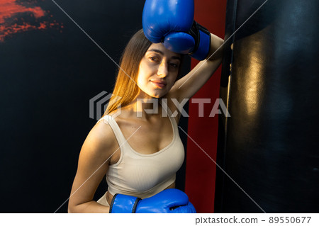 Portrait of a girl fighter in gloves near a punching bag 89550677