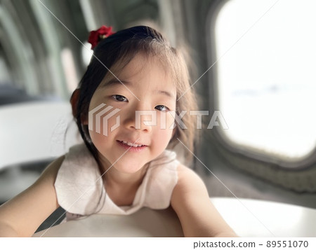 Beautiful little girl smiles on the table with white space background 89551070