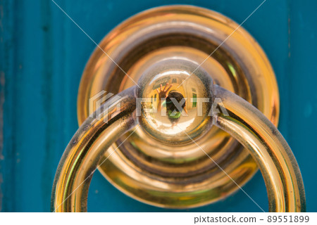 Golden door knocker on a blue wooden door 89551899