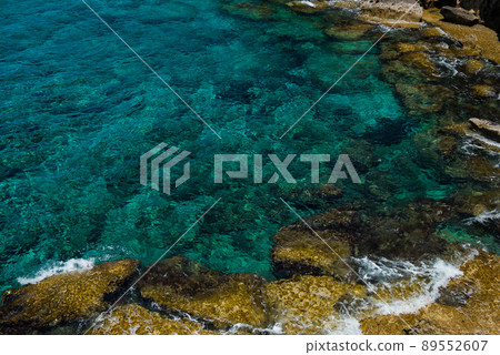 Crystal clear turquoise sea water background and rocky coast Crystal clear turquoise sea water background and rocky coast 89552607