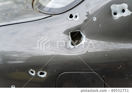 Close-up of the body of the shelled car. A sedan with through holes from shrapnel and bullets. The war in Ukraine 2022. Russian aggression. Shelling of civilians. War crimes concept Close-up of the body of the shelled car. A sedan with through holes from shrapnel and bullets. The war in Ukraine 2022. Russian aggression. Shelling of civilians. War crimes concept 89552751
