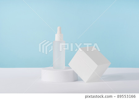 Serum cosmetic bottle with peptides and retinol on platform pedestal on blue background. Oil cosmetics transparent fashion product packaging with stylish props. Serum beauty dropper mock up Serum cosmetic bottle with peptides and retinol on platform pedestal on blue background. Oil cosmetics transparent fashion product packaging with stylish props. Serum beauty dropper mock up 89553166