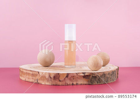 Cosmetic liquid foundation nude cream bottle mockup on wooden podium and decor balls. Beige concealer base cosmetics product mock up on pink background. Skincare beauty primer, cc corrector 89553174