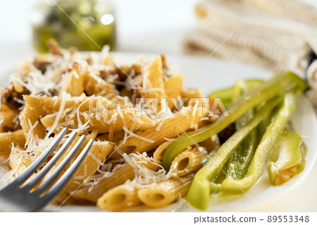 Closeup of colorful delicious pasta with meat and vegetables dressing on white plate. 89553348