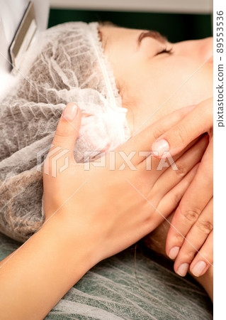 Facial massage. Hands of a masseur massaging neck of a young caucasian woman in a spa salon, the concept of health massage Facial massage. Hands of a masseur massaging neck of a young caucasian woman in a spa salon, the concept of health massage 89553536