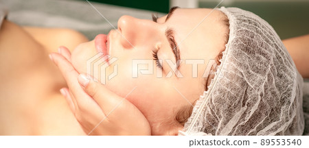 Facial massage. Hands of a masseur massaging neck of a young caucasian woman in a spa salon, the concept of health massage 89553540