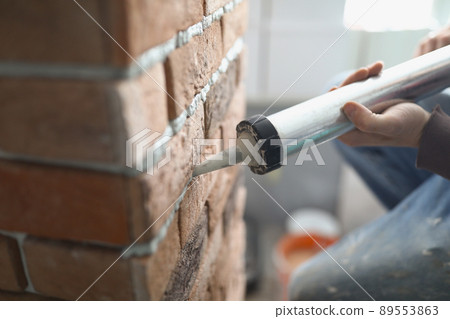Construction worker put foal from special gun into empty brick space Construction worker put foal from special gun into empty brick space 89553863