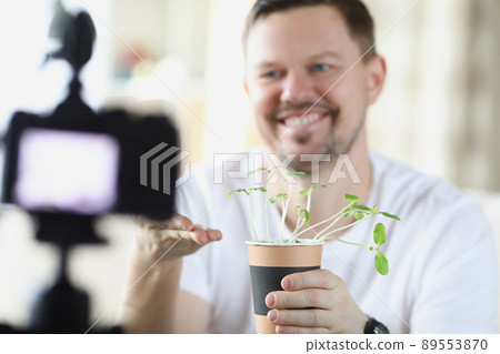 Middle aged man recording on video how he growing plants at home Middle aged man recording on video how he growing plants at home 89553870