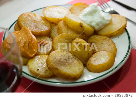 Traditional Spanish fried potatoes Patatas bravas served with cheese sauce and spicy sauce with paprika and chili Traditional Spanish fried potatoes Patatas bravas served with cheese sauce and spicy sauce with paprika and chili 89553872