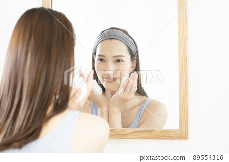 A woman who looks in the mirror and smiles 89554316