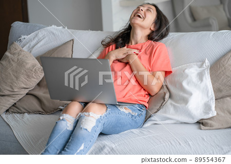 The girl lies on the couch with a laptop. Video communication. Distance jobr, freelance. Work from home The girl lies on the couch with a laptop. Video communication. Distance jobr, freelance. Work from home 89554367