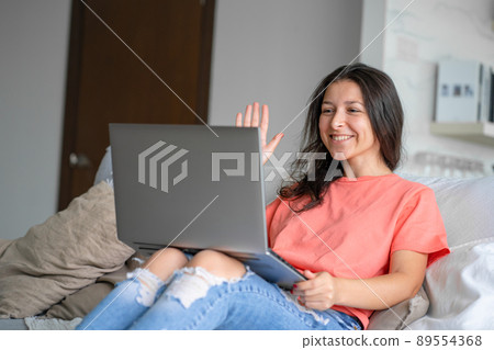The girl lies on the couch with a laptop. Video communication. Distance jobr, freelance. Work from home The girl lies on the couch with a laptop. Video communication. Distance jobr, freelance. Work from home 89554368
