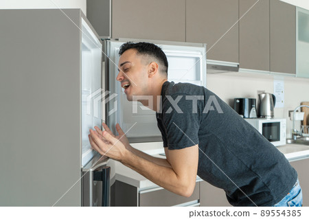 On a hot day, the guy cools with his head in the refrigerator. Broken air conditioner 89554385