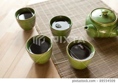 green teapot and teacups. hot drink on wooden table. Organic product from the nature for healt green teapot and teacups. hot drink on wooden table. Organic product from the nature for healt 89554509