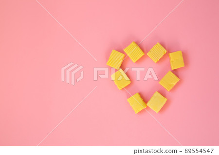 The candy is laid out in the form of a heart. A heart of chewy candies on a pink background. Valentine's Day greeting card. Template for the design. copy space. The candy is laid out in the form of a heart. A heart of chewy candies on a pink background. Valentine's Day greeting card. Template for the design. copy space. 89554547