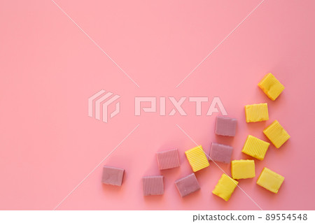Chewy yellow candies on a pink background. Template for the design. Candy on the edge of the background. Greeting card for bakers. copy space. Chewy yellow candies on a pink background. Template for the design. Candy on the edge of the background. Greeting card for bakers. copy space. 89554548