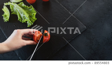 Woman is cutting cherry tomatoes for the salad Woman is cutting cherry tomatoes for the salad 89554803