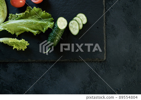 Cucumber and salad leaves on dark slate texture Cucumber and salad leaves on dark slate texture 89554804