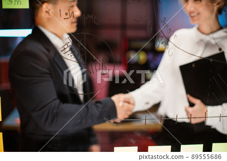 Male and female business colleagues, shaking hands after finishing up the meeting in modern office Male and female business colleagues, shaking hands after finishing up the meeting in modern office 89555686