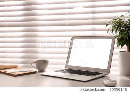 Laptop on desk near window in office. Comfortable workplace Laptop on desk near window in office. Comfortable workplace 89556148