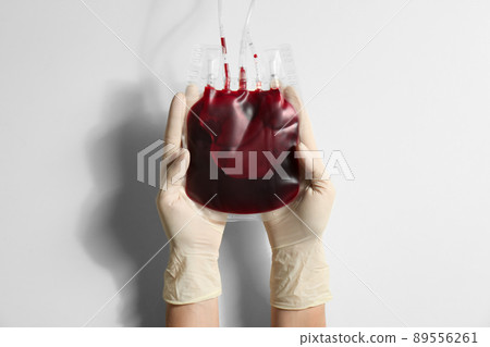Woman holding blood for transfusion on light background, closeup. Donation concept Woman holding blood for transfusion on light background, closeup. Donation concept 89556261
