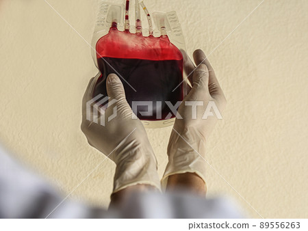 Woman holding blood for transfusion on beige background, closeup. Donation concept 89556263