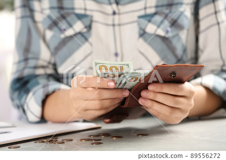 Woman counting money at light grey table, closeup 89556272