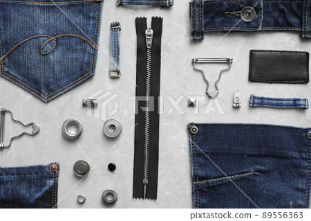 Flat lay composition with garment accessories and cutting details for jeans on grey marble background 89556363
