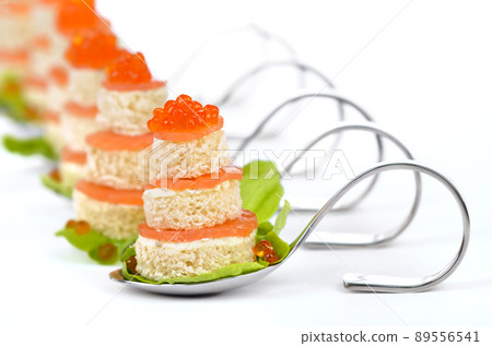 Tidbits with smoked salmon, caviar, cream cheese and toast on party spoons, lemons in the background 89556541