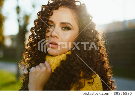 close-up. A brooding look at a beautiful girl with green eyes and makeup smoky holding her hand behind the gates of a yellow sweater 89556880