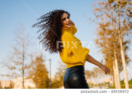girl in autumn park whirls and her curly long hair fluttering in the wind 89556972
