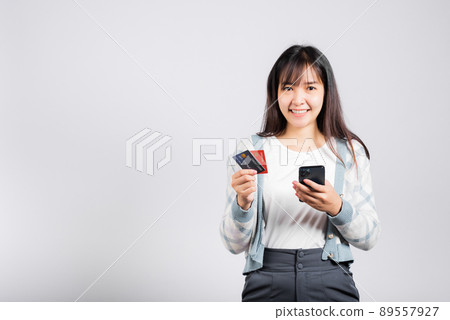Woman excited smiling hold mobile phone and plastic debit credit bank card for payment Woman excited smiling hold mobile phone and plastic debit credit bank card for payment 89557927