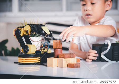 Happy Asian little kid boy using remote control playing robotic machine arm for pick up wood block Happy Asian little kid boy using remote control playing robotic machine arm for pick up wood block 89557972